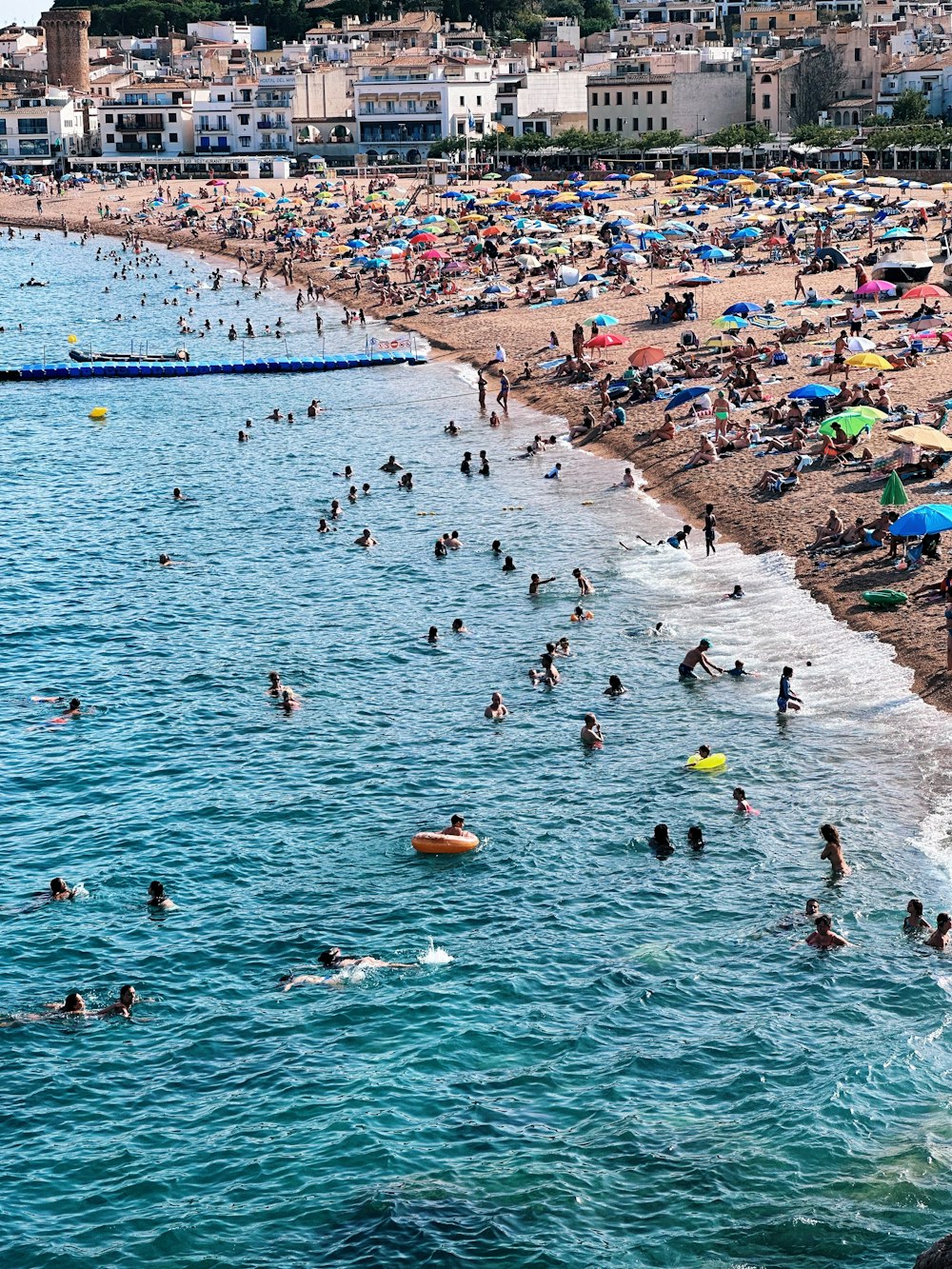 a crowded beach with people swimming in the water