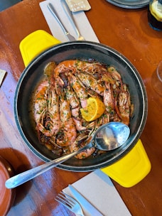 Close-up of a beautifully plated grilled prawn dish garnished with fresh herbs and lemon wedges.