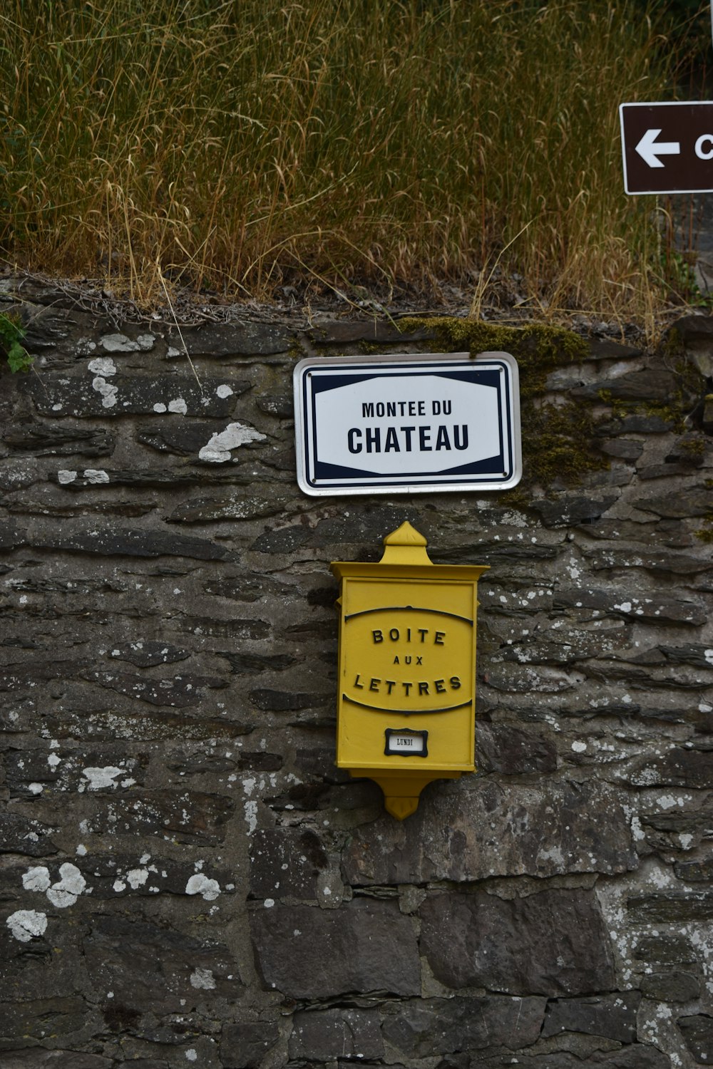 a street sign on the side of a stone wall