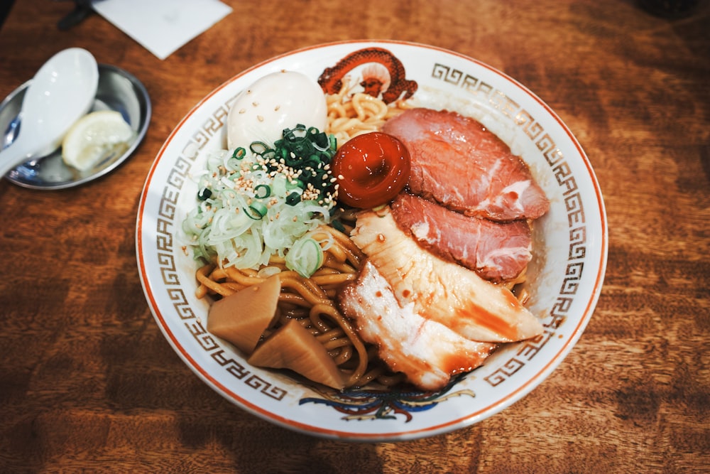 a plate of food with meat, noodles and vegetables