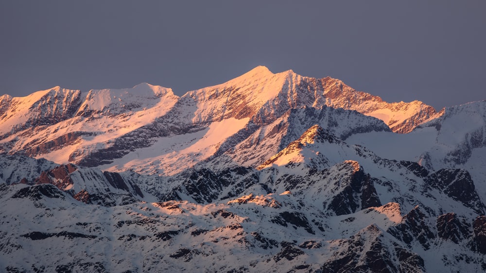 a snow covered mountain range at sunset