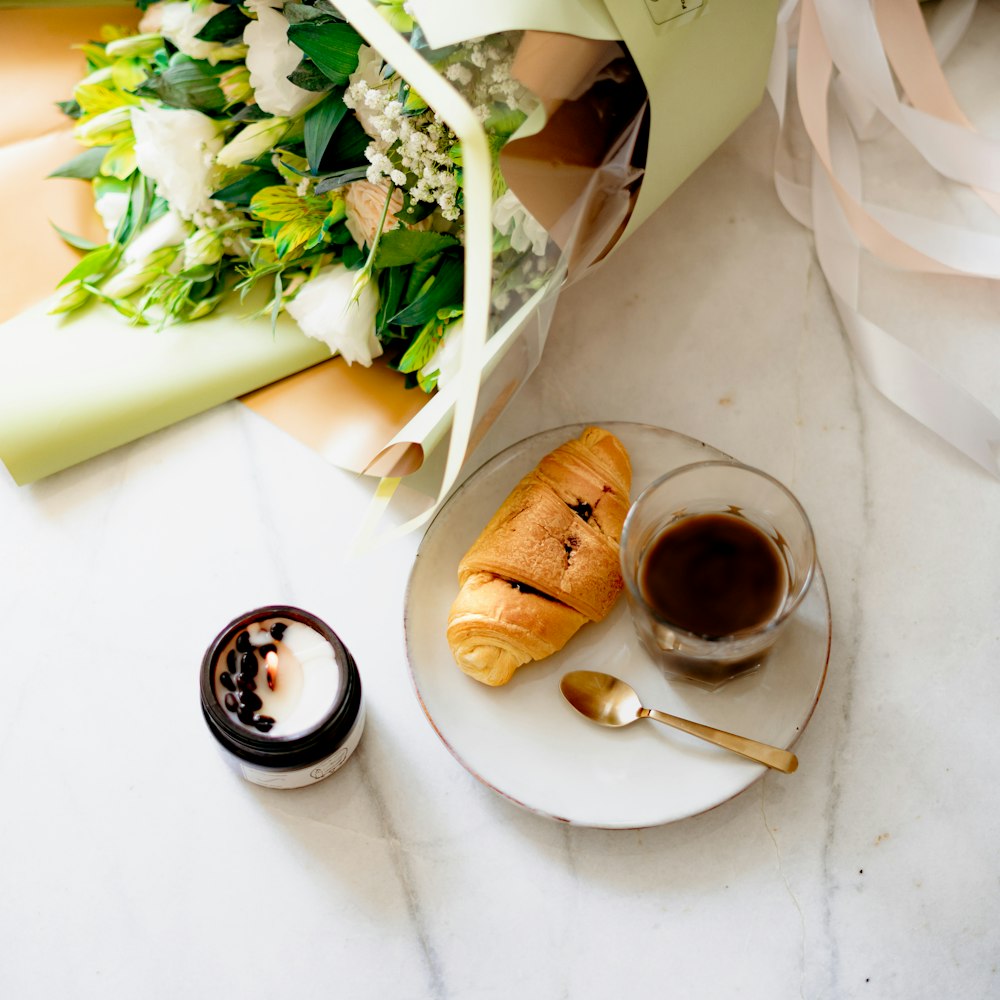 a plate with a croissant and a cup of coffee