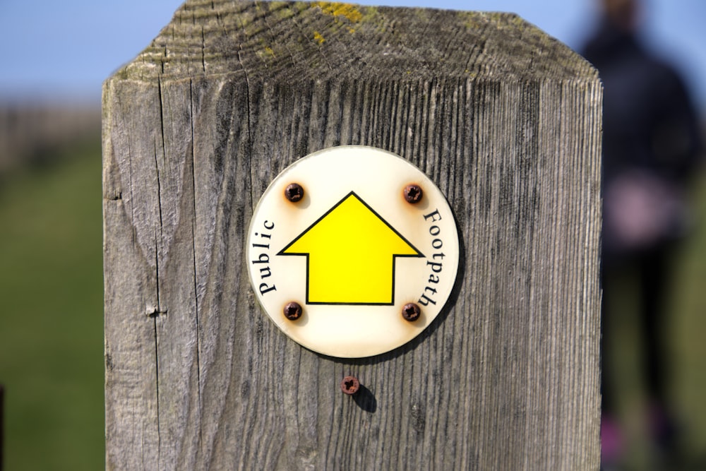 un panneau sur un poteau en bois avec une maison jaune dessus