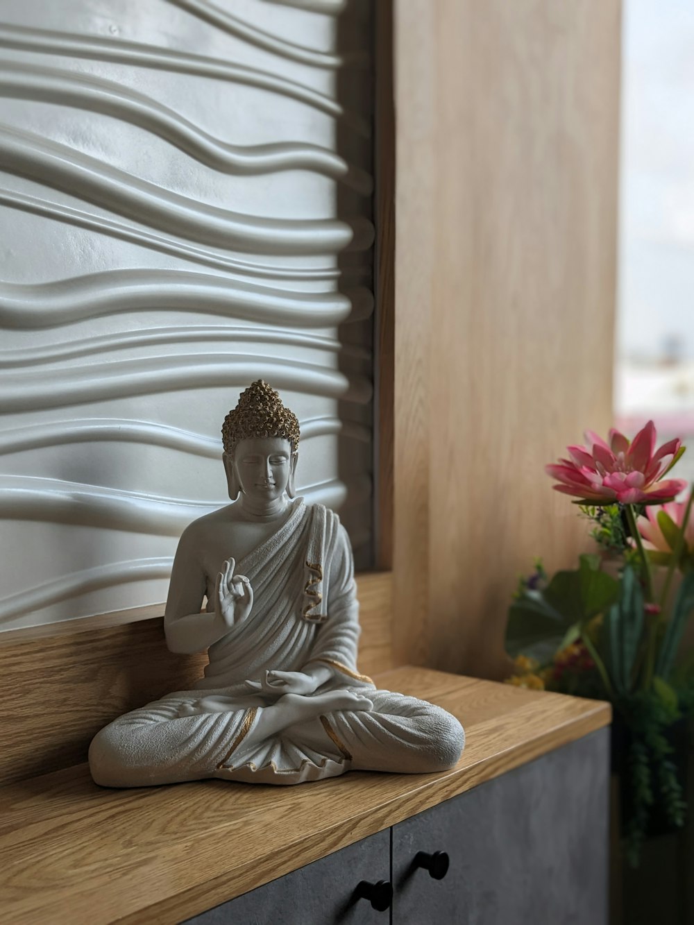 a buddha statue sitting on top of a wooden shelf