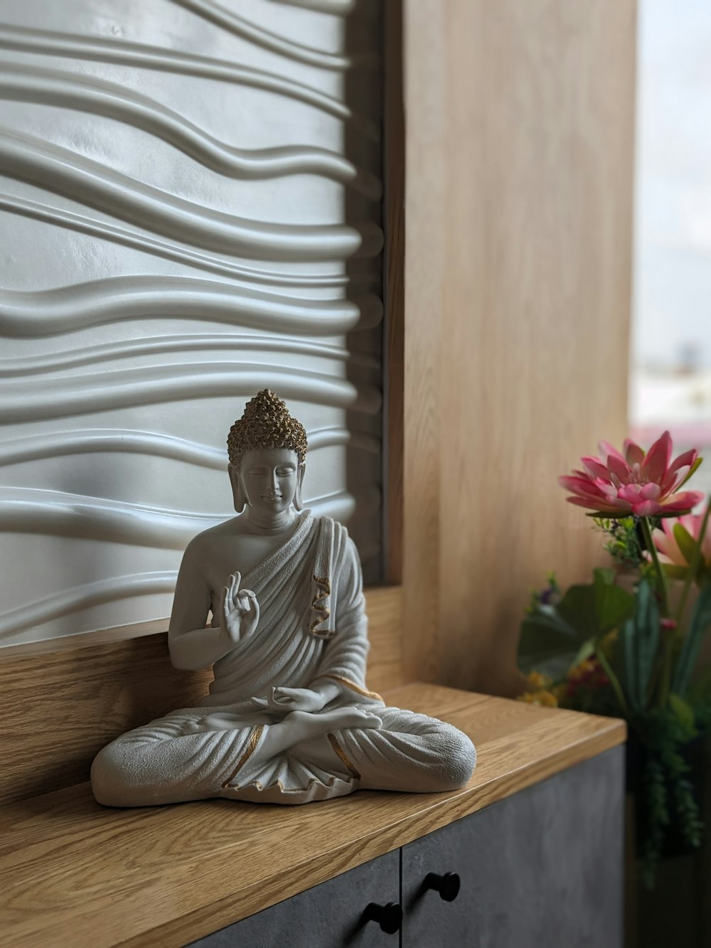 Una estatua de Buda sentada encima de un estante de madera