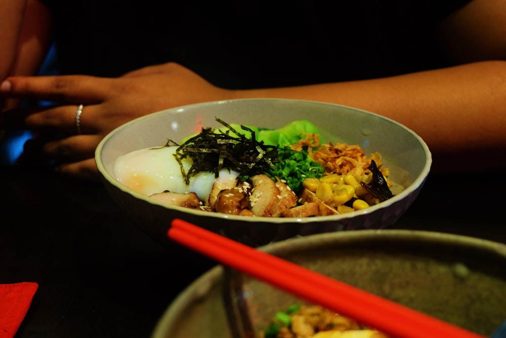 a bowl of food on a table with chopsticks