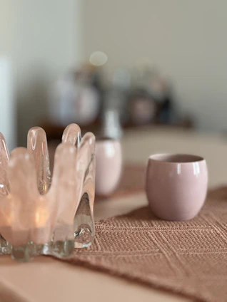 A softly lit coffee cup resting on a cream-colored linen napkin with blush and terracotta accents in the background.