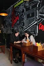 A couple happily reviewing travel plans on a tablet at a cozy café.