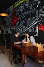 A happy couple chatting on a mobile dating app in a cozy café setting.