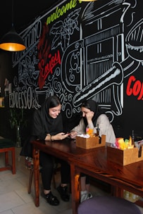 A happy couple chatting on a mobile dating app in a cozy café setting.