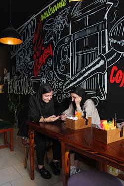 A smiling couple holding their credit cards while sitting at a cozy café table.