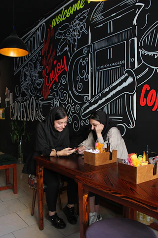 A cozy urban café scene where two people are exchanging Snapchat usernames.