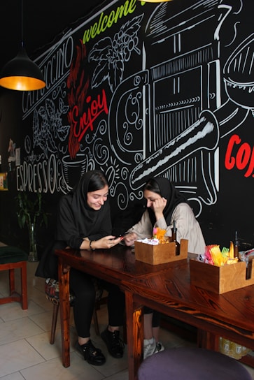 A smiling couple holding their credit cards while sitting at a cozy café table.
