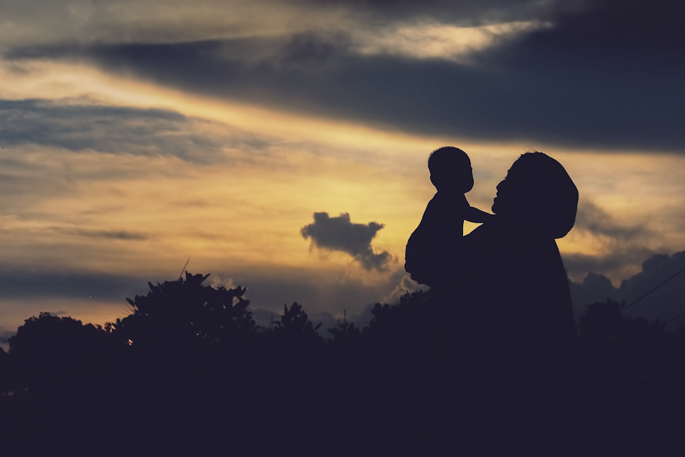 a silhouette of a woman holding a child