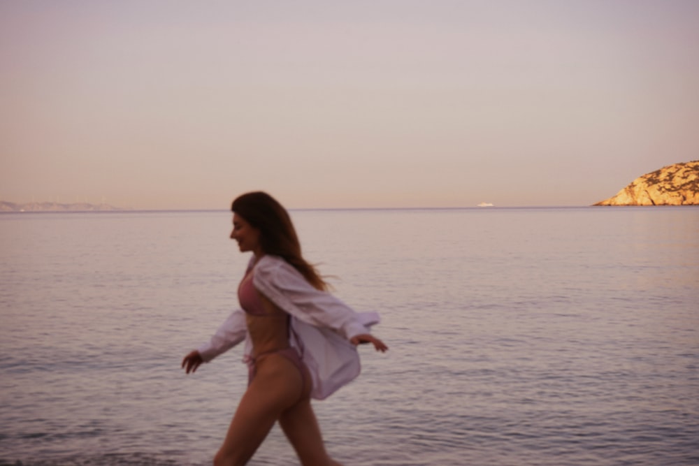 a woman walking along a beach next to the ocean