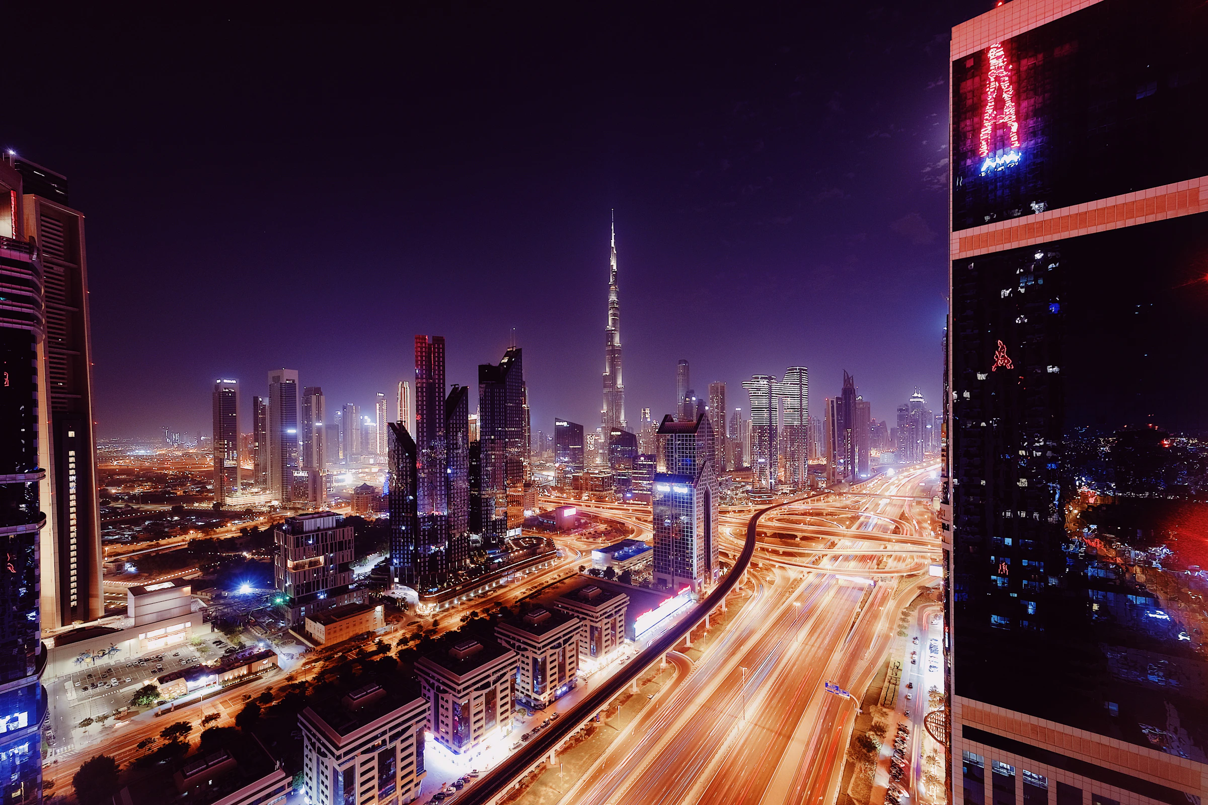 Dubai at night from above, with highways of light running between towers
