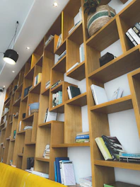 A sturdy brown bookshelf filled with books and decorative items against a brown wall