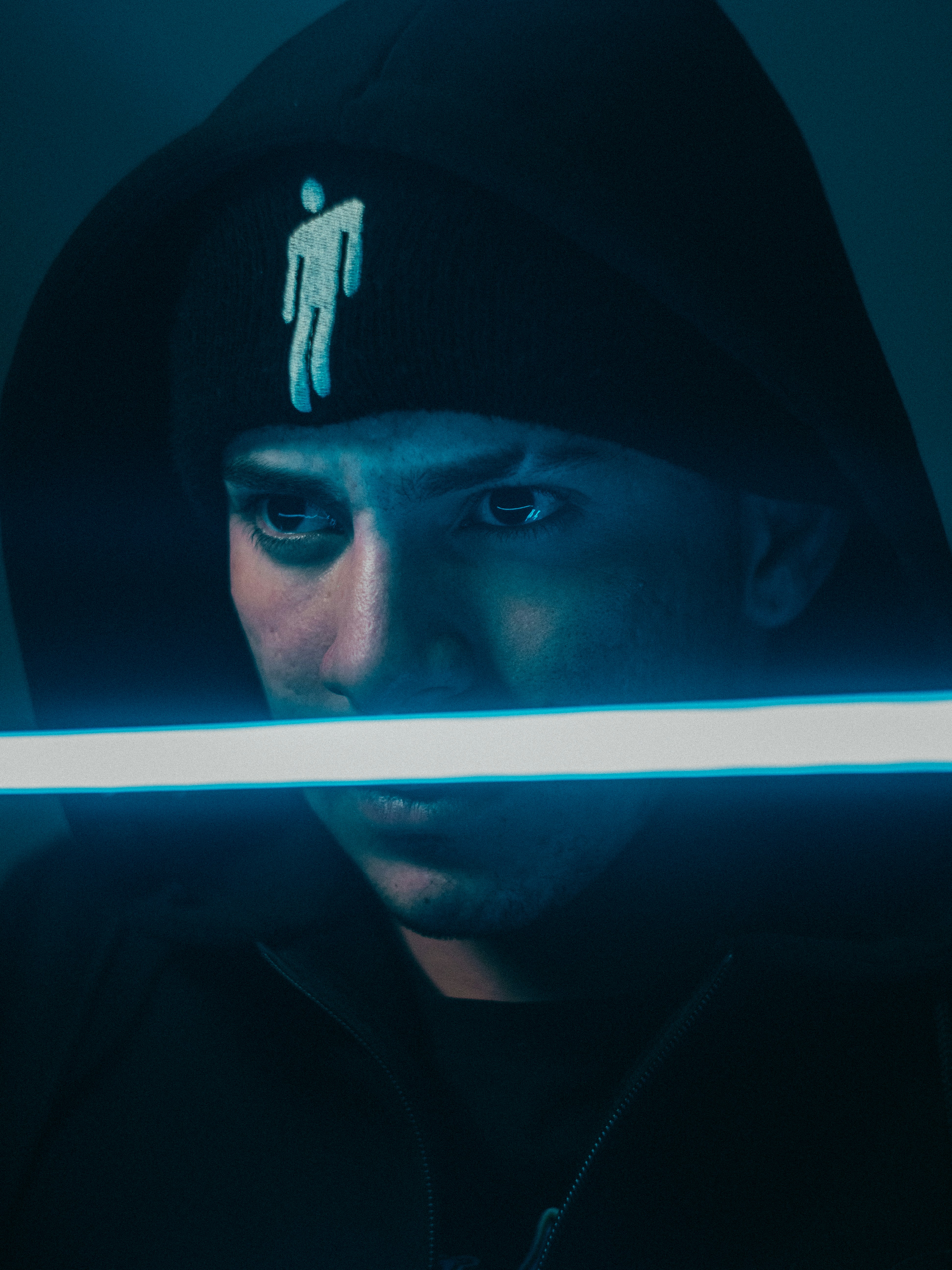 Ein Mann in einem schwarzen Kapuzenpullover mit einem weißen Stock in der Hand