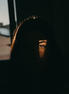 a woman's face is seen through the shadow of a window