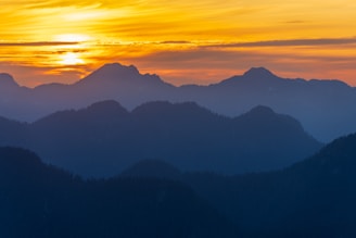 the sun is setting over a mountain range