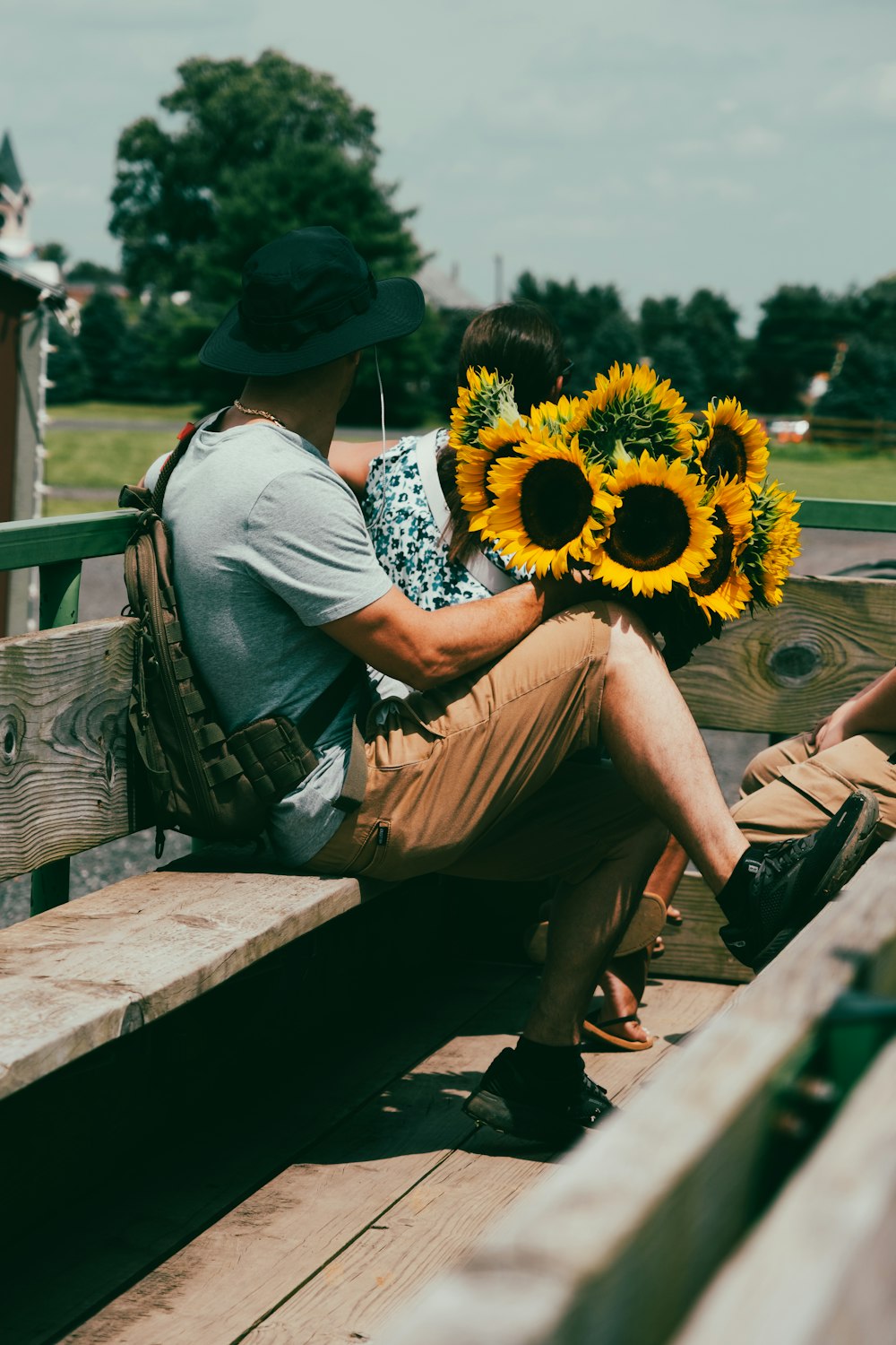 a man and woman sitting on a bench with a sunflower