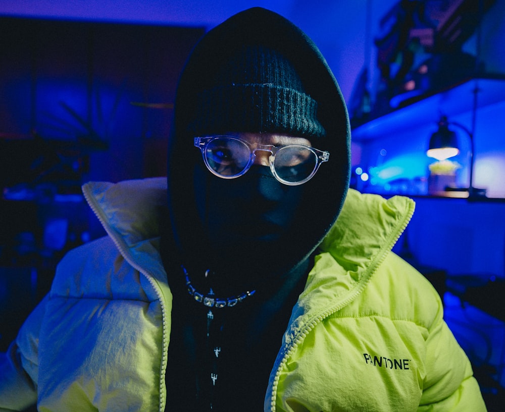 a man wearing a hoodie and glasses in a dark room
