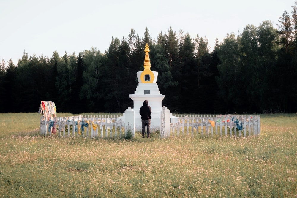 a person standing in a field next to a white fence