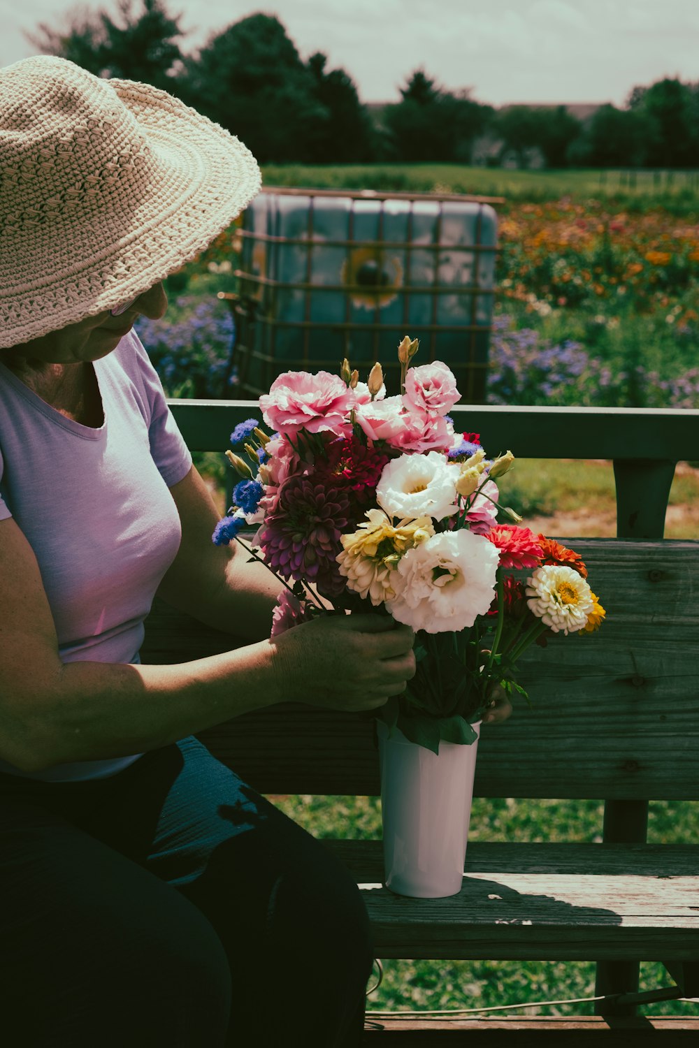 a woman sitting on a bench holding a bouquet of flowers