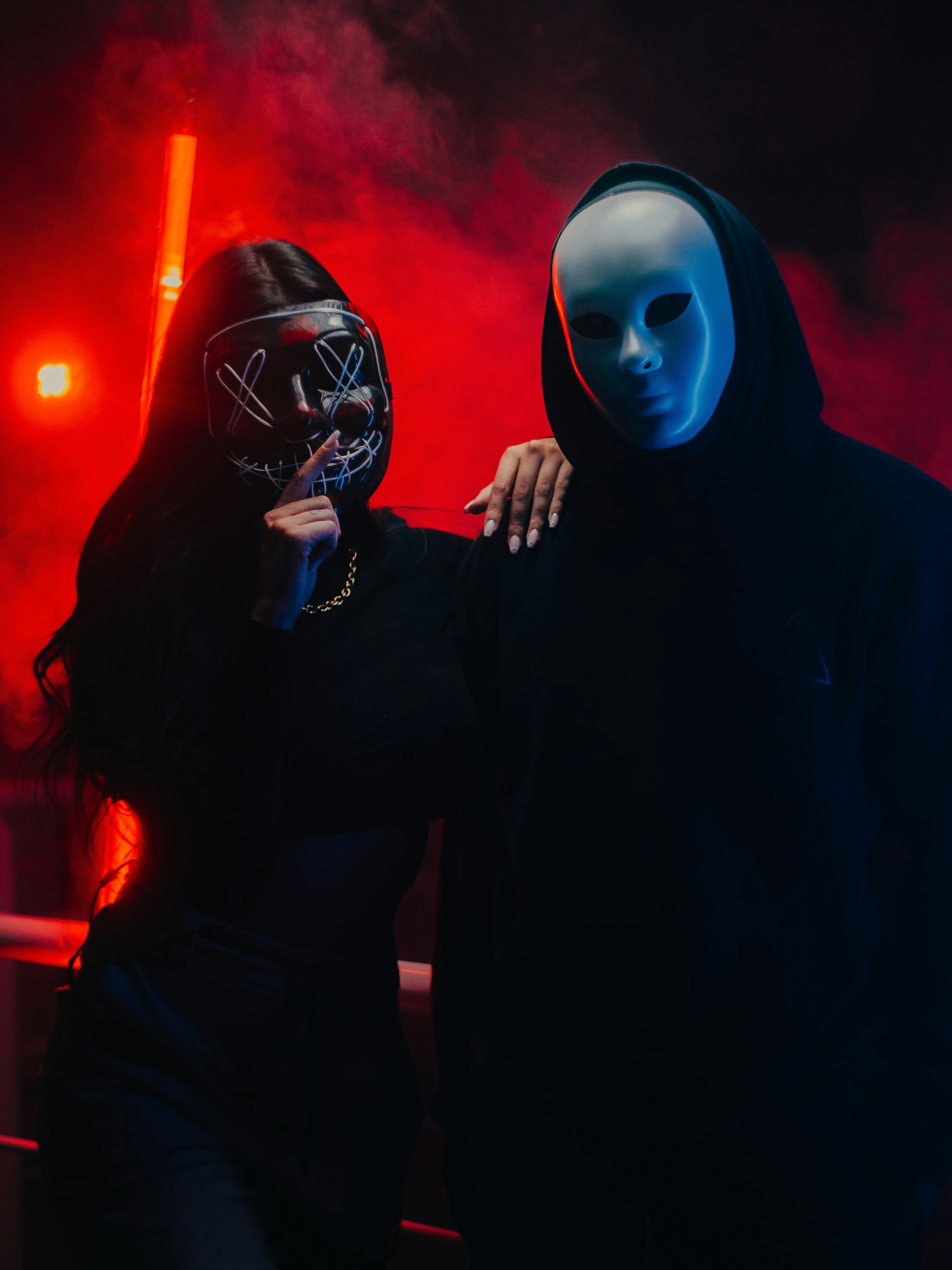 a man and a woman wearing masks standing in front of a red light