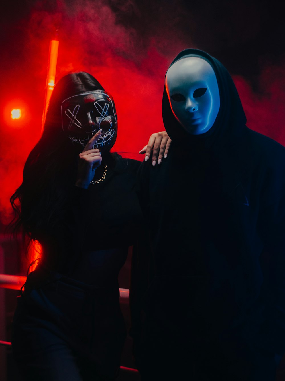 a man and a woman wearing masks standing in front of a red light