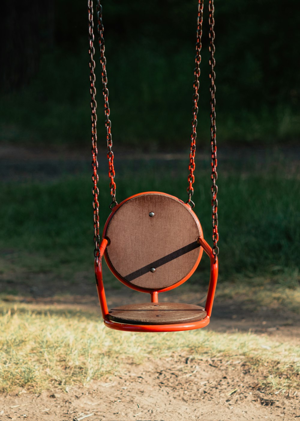 a wooden swing hanging from a chain in a park
