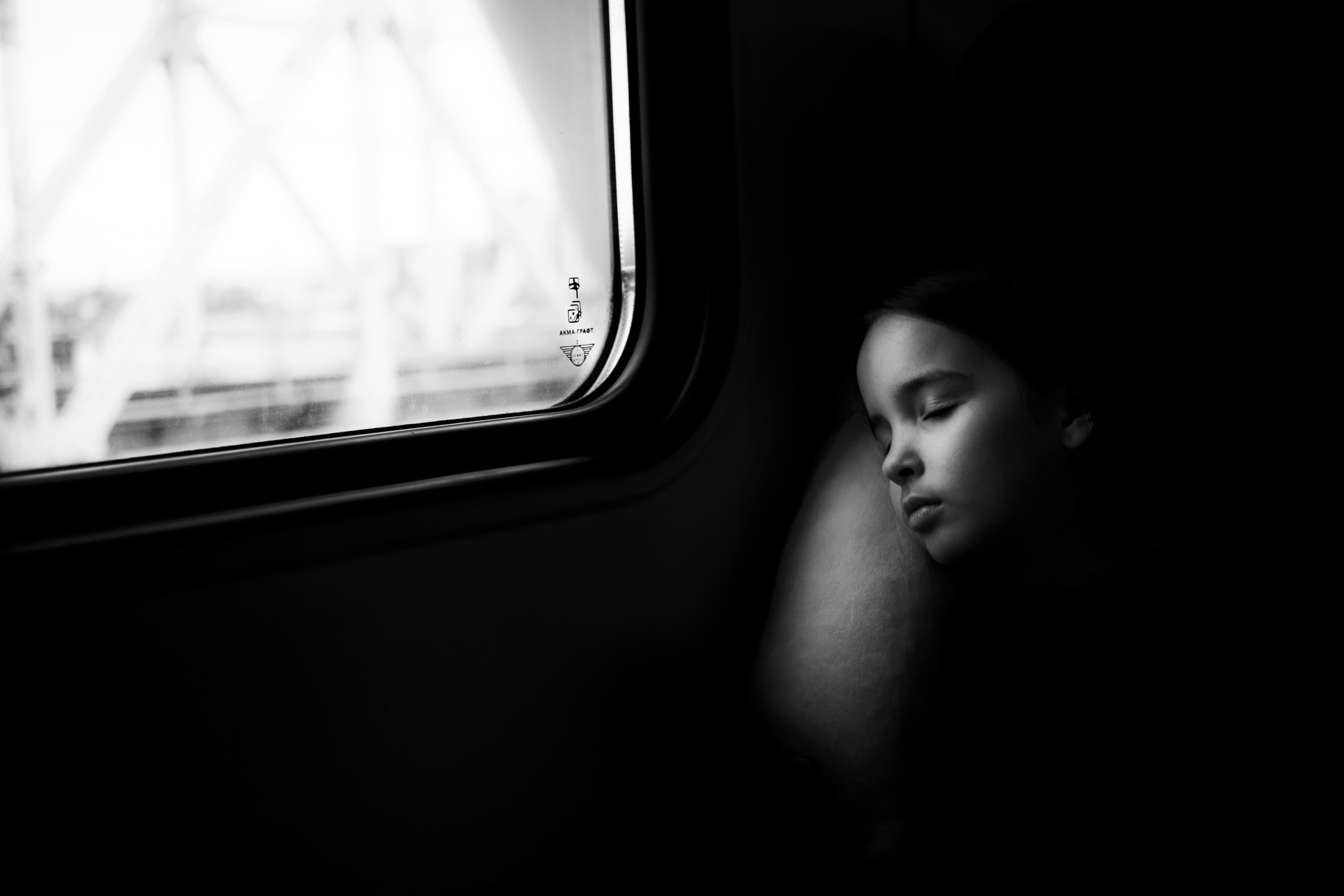 a woman sleeping on a train next to a window, Sleeping on the train.