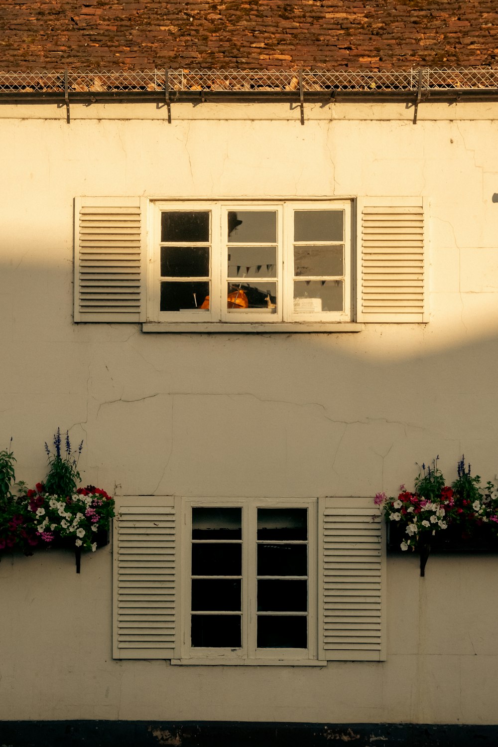 a white building with two windows and some flowers