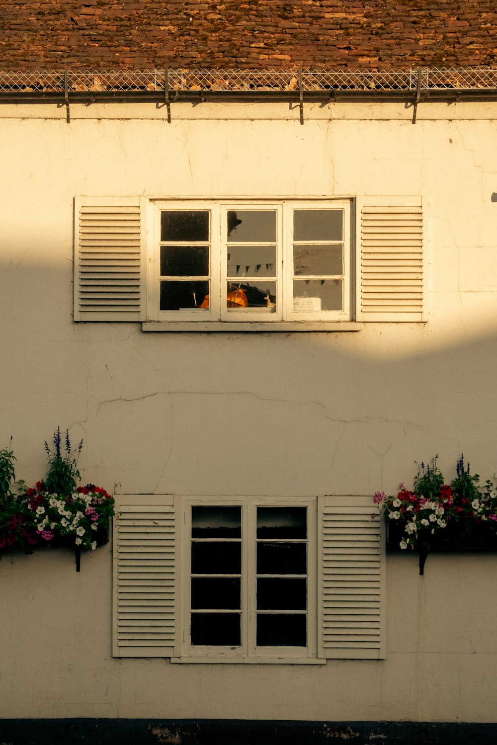 Un edificio bianco con due finestre e alcuni fiori