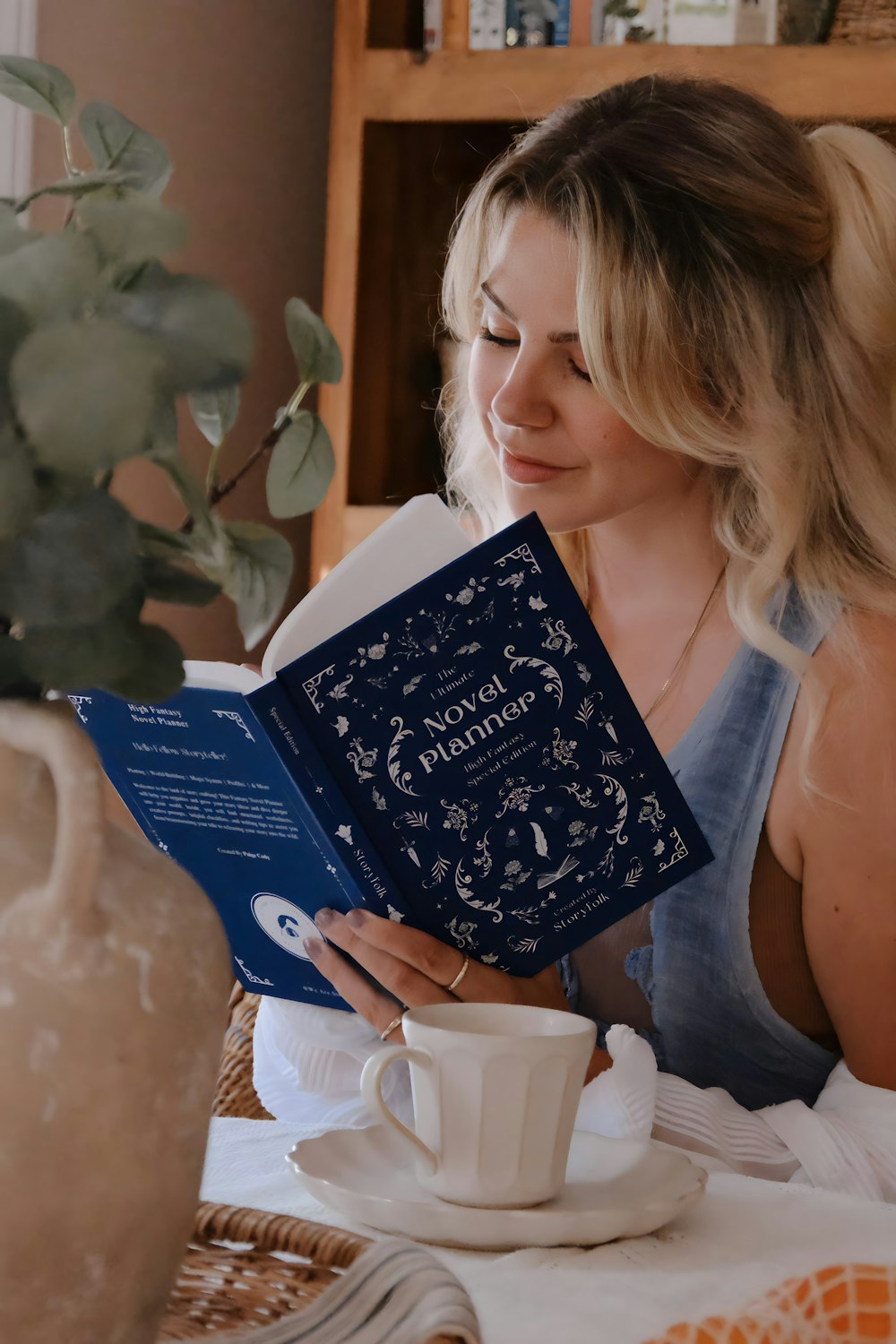 a woman sitting at a table reading a book