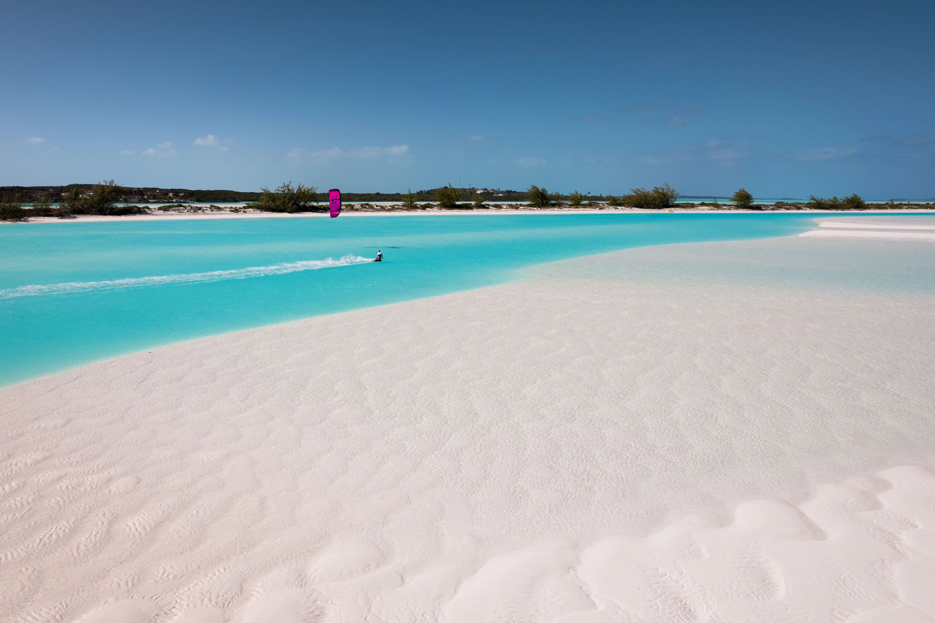 Parasailing above turquoise water and a white-sand beach