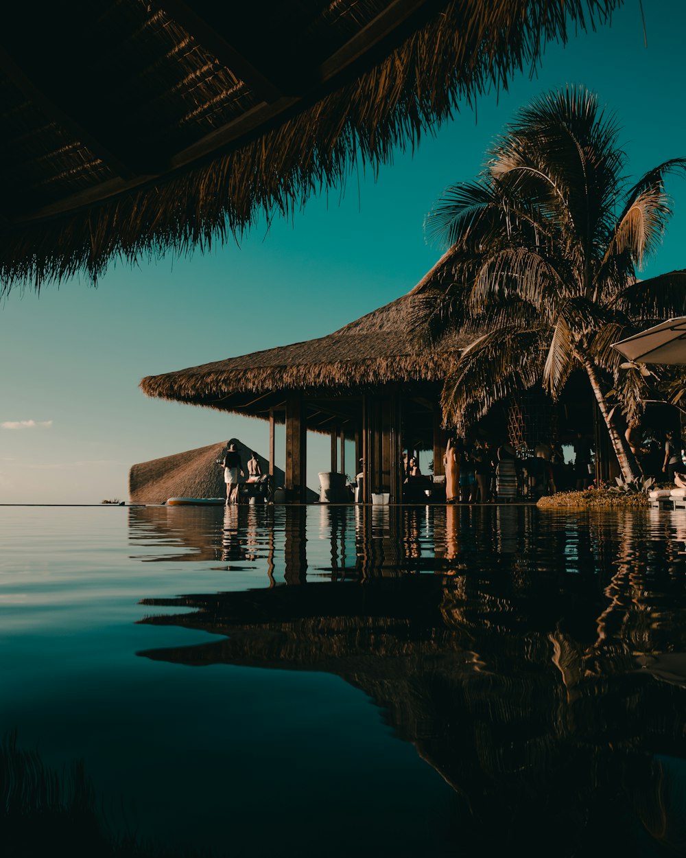 a group of people standing on a beach next to a hut