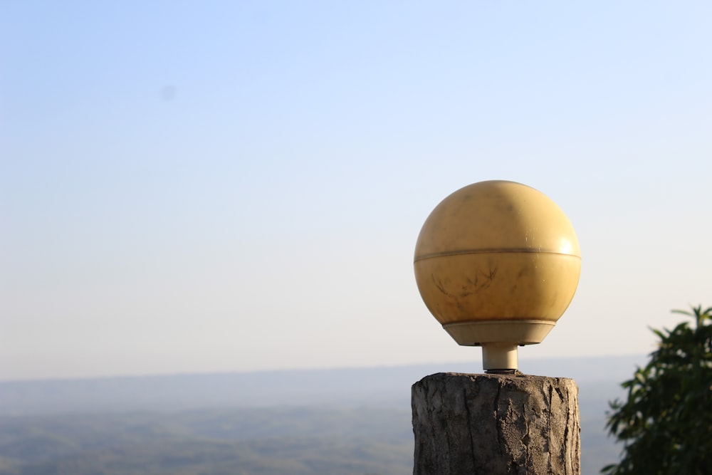 una bola amarilla encima de un poste de madera