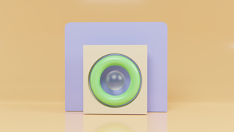 A minimalist composition featuring geometric shapes with a pastel color palette. In the foreground is a square structure with a circular, green-bordered element resembling a speaker or lens. The backdrop consists of a soft purple rectangle set against a warm beige background.