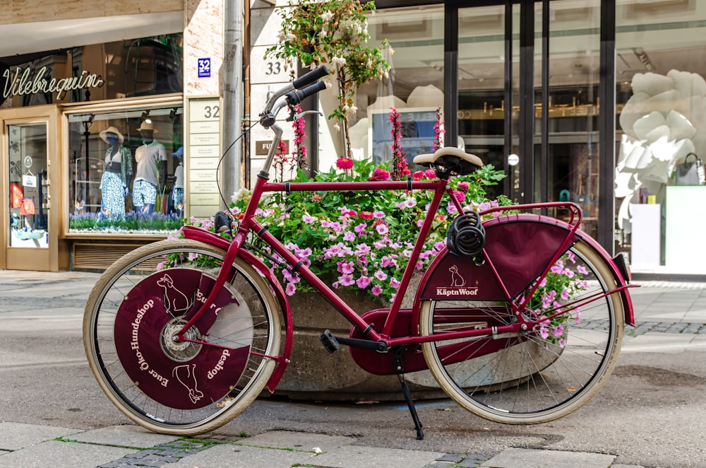 a red bicycle parked next to a flower pot