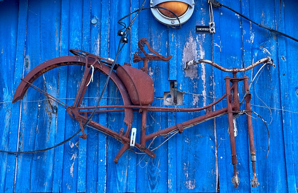 an old rusty bicycle hanging on the side of a blue building
