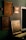 Several framed art pieces are displayed on a dark green wall. The frames are ornate with classic designs, and one of the paintings appears to have historical or classical themes. A large mirror with a simple white frame is also visible.