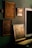 Several framed art pieces are displayed on a dark green wall. The frames are ornate with classic designs, and one of the paintings appears to have historical or classical themes. A large mirror with a simple white frame is also visible.