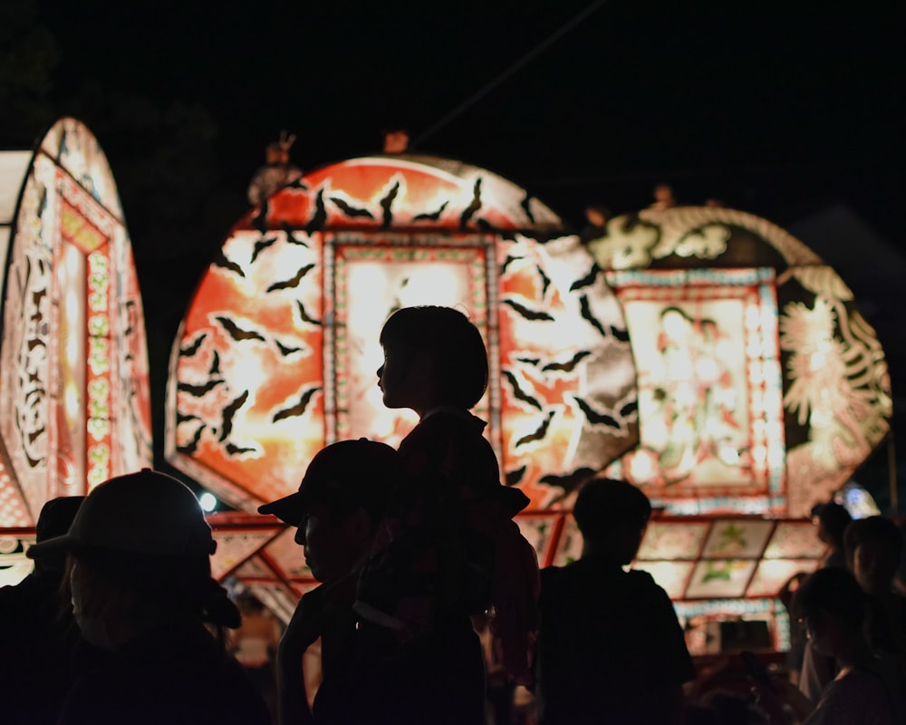 a crowd of people standing around a carnival ride at night