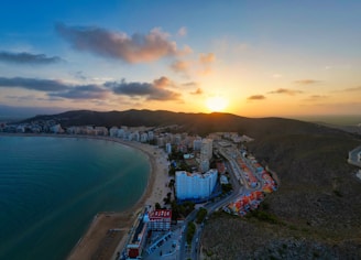 an aerial view of a beach with a sunset in the background