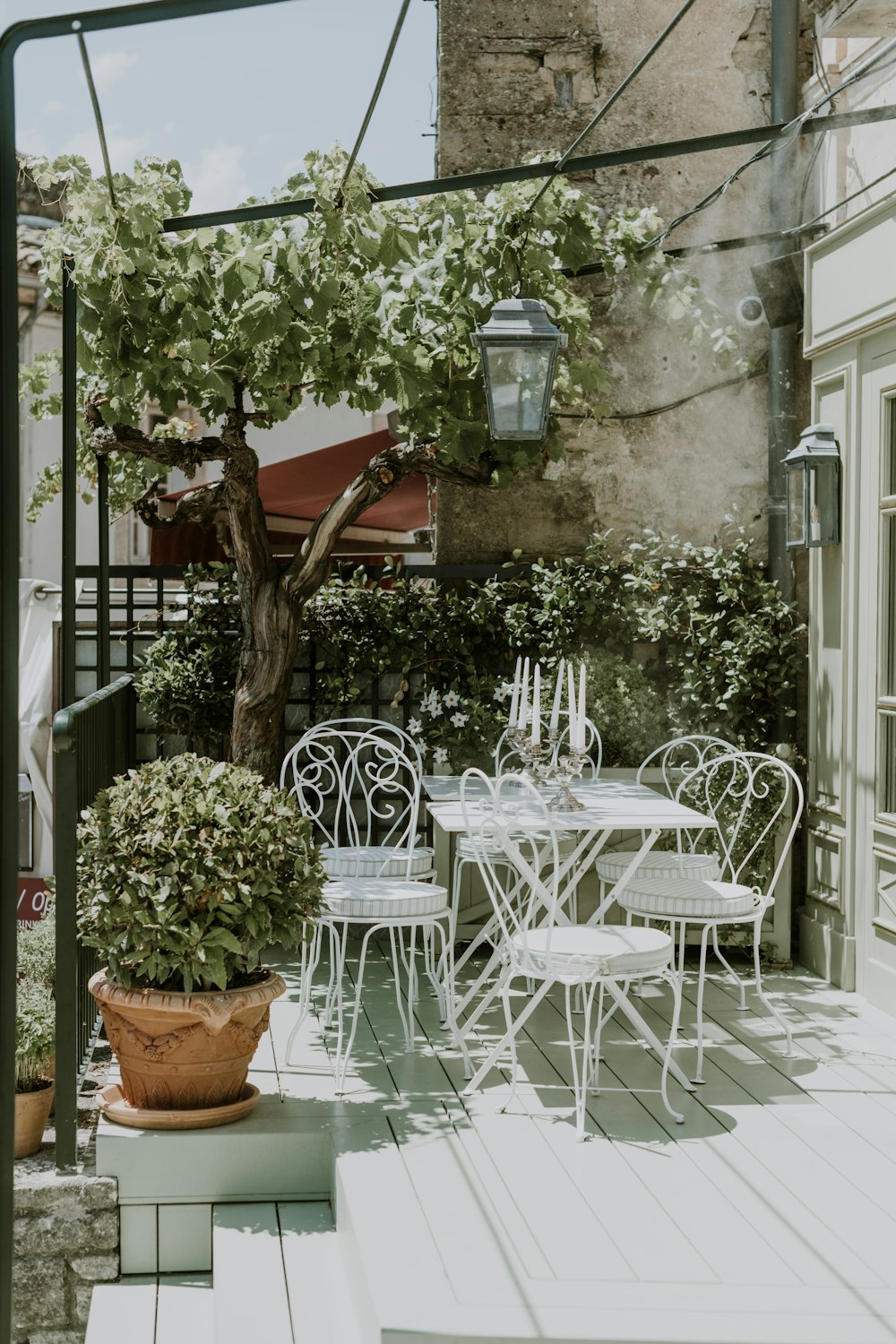 a patio with a table and chairs and a potted tree