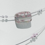 A delicate bracelet with two parallel silver wires adorned with multiple spherical beads and an elliptical, transparent centerpiece. The centerpiece features embedded pink floral motifs, adding elegance to the design. The beads vary in size and some appear to have a subtle purple hue. The backdrop is a textured, pale surface casting soft shadows.