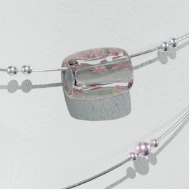 A delicate bracelet with two parallel silver wires adorned with multiple spherical beads and an elliptical, transparent centerpiece. The centerpiece features embedded pink floral motifs, adding elegance to the design. The beads vary in size and some appear to have a subtle purple hue. The backdrop is a textured, pale surface casting soft shadows.