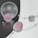 A composition of elegant jewelry pieces featuring pastel pinks and silver tones. Delicate strings of pearls and beads are artfully arranged around smooth, translucent orbs and geometric shapes, reflecting light on a neutral background.