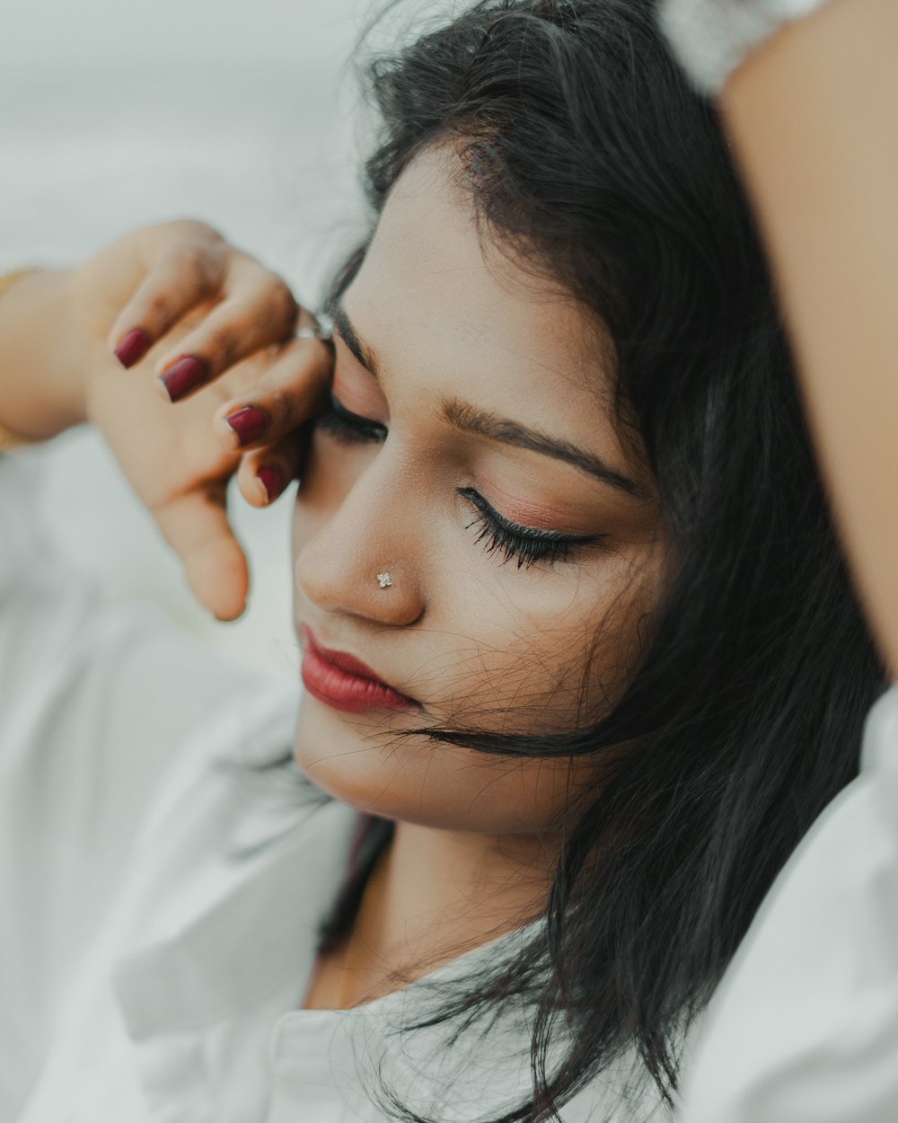 a woman with dark hair and a nose piercing